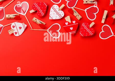 Verschiedene herzförmige Dekorationen auf rotem Hintergrund mit viel Kopierraum, perfekt für romantische Grußkarten, Valentinstag- und Liebesmotive Stockfoto