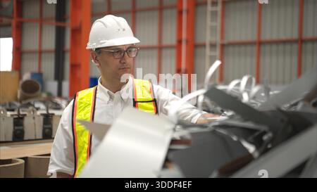 Industriearbeiter, der in einem großen Metallrohr in einer Fabrik einen Schutzhelm trägt || Modell veröffentlicht Stockfoto