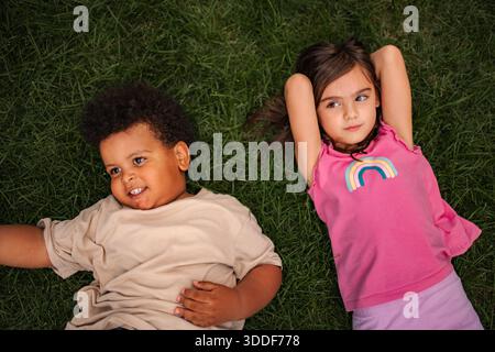 Verschiedene Kinderfreunde liegen zusammen auf Gras Stockfoto