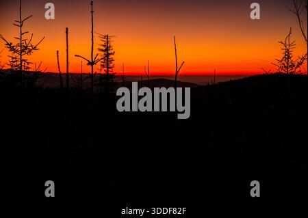 Ein minimalistischer Sonnenuntergang vom Pass zwischen Szyndzielnia und Klimczok, mit einem klaren Horizont und mehrschichtigen Bergsilhouetten. Stockfoto