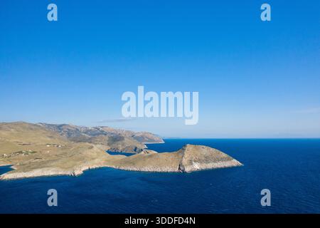 Weite Aussicht aus der Luft auf einen sonnenverwöhnten Felsvorsprung, umgeben von leuchtend blauem Mittelmeerwasser am Cap Tenare, Griechenland. Die Szene bietet zerklüftete Hügel, eine offene Küste und einen weiten, klaren Himmel für ein Gefühl von Raum und Ruhe. Stockfoto