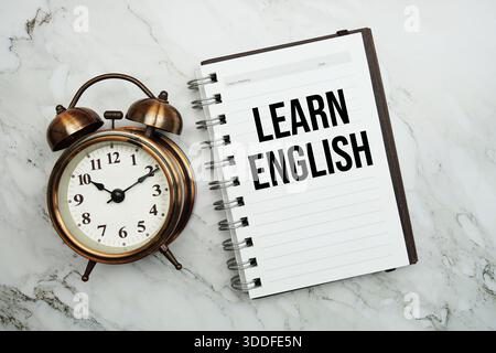 Lernen Sie englischer Text auf Notizblock mit Wecker Stockfoto