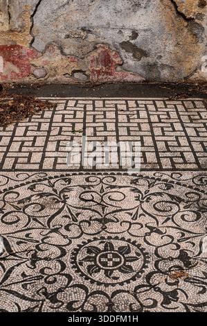 Hadrians Villa, Tivoli, Latium, Italien: Spuren römischer roter Fresko-Dekoration sind an der Innenwand des Erdgeschosses neben einem aufwendigen geometrischen schwarz-weißen Fußbodenmosaik im Gästehaus Hospitalia für Beamte der mittleren Klasse erhalten, die die Villa Adriano leiten, erbaut 118–138 n. Chr. als Rückzugsort aus Rom und luxuriöser Lustpalast für Kaiser Hadrian (regierte 117–138 n. Chr.). Stockfoto