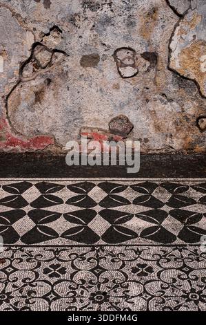 Hadrians Villa, Tivoli, Latium, Italien: Überreste römischer roter Fresko-Dekoration sind auf der Innenwand des Erdgeschosses neben einem aufwendigen geometrischen schwarz-weißen Fußbodenmosaik im Gästehaus Hospitalia für Beamte der mittleren Klasse erhalten, die die Villa Adriano leiten, erbaut 118–138 n. Chr. als Rückzugsort aus Rom und luxuriöser Lustpalast für Kaiser Hadrian (regierte 117–138 n. Chr.). Stockfoto