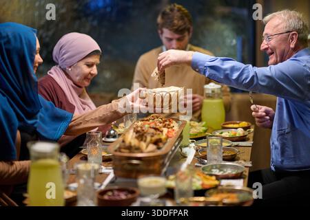 Die muslimische Familie genießt während des Ramadan iftar gemeinsam in einem Restaurant mit festlicher Dekoration und gemeinsamen Speisen Stockfoto