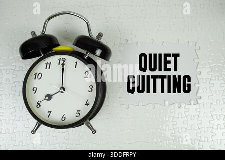 Puzzle mit einem fehlenden Stück mit „Quiet quitting“ und Wecker auf weißem Hintergrund Stockfoto