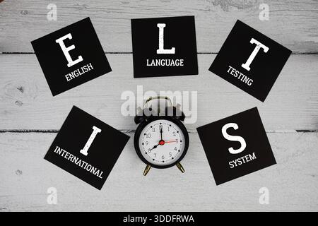 IELTS International English Language Testing System mit Wecker auf hölzernem Hintergrund Stockfoto