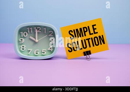 Einfacher Lösungstext und Wecker auf blauem und violettem Hintergrund Stockfoto