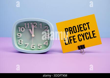 Text des Projektlebenszyklus und Wecker auf blauem und violettem Hintergrund Stockfoto