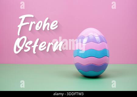 Osterei mit Text „Frohe Osteru German Easter Greetings“ auf rosa und grünem Hintergrund Stockfoto