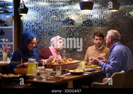 Familie genießt iftar gemeinsam in einem warmen Restaurant mit Ramadan-Dekoration und traditionellen Speisen Stockfoto