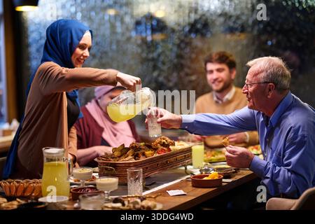 Die muslimische Familie genießt iftar gemeinsam in einem Restaurant, das für den Ramadan dekoriert ist Stockfoto