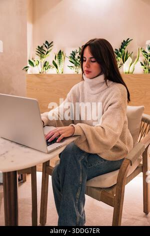 Frau, die ferngesteuert am Laptop am Marmortisch arbeitet Stockfoto