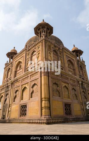 Blick aus dem niedrigen Winkel auf ein kunstvolles Mausoleum aus der Mogul-Ära mit komplizierten Sandsteinschnitzereien und Kuppeln in Khusro Bagh in Prayagraj. Warmes Sonnenlicht betont die geometrischen Details und die historische Architektur vor einem klaren Himmel. Stockfoto