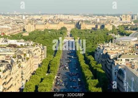 Blick von der Sonne auf die Avenue des Champs-Elysees, die von üppigen grünen Bäumen umgeben ist, führt an einem klaren Sommertag in Richtung des historischen Louvre-Museums im Zentrum von Paris. Stockfoto