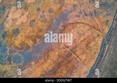 Draufsicht mit dem Kontrast zwischen dunklem Flusswasser und verwelktem Gras. Die stimmungsvolle Atmosphäre der Spätherbstlandschaft weckt ein Gefühl von Kälte, Stille und natürlicher Depression. Stockfoto