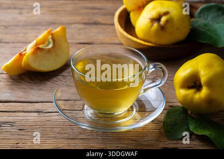 Heißer Quittentee in transparenter Teekanne mit frischem Obst auf einem Holztisch Stockfoto
