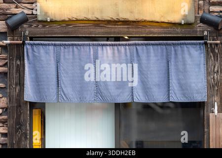 Der Vorhang-ähnliche Stoff, der vor traditionellen japanischen Restaurants und Geschäften hängt, dient nicht nur als Schild, sondern hat eine größere Bedeutung, Stockfoto