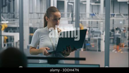 Frau überwacht automatisierte Systeme auf einem Laptop. Technischer Spezialist für die Laptop-Prüfung oder -Diagnose automatisierter Industriesysteme. Systemüberwachung in Echtzeit, Diagnose vor Ort, Prozessoptimierung. Stockfoto