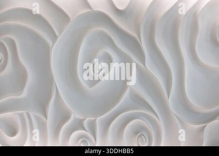 Abstrakte weiße geformte Wand mit eleganten blumeninspirierten Motiven und fließenden organischen Formen, monochromatische dekorative Oberfläche mit sanften Kurven Stockfoto