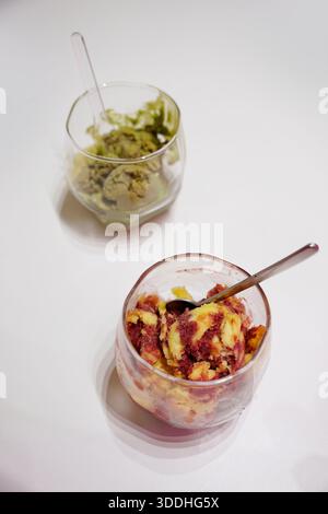Matcha-Eis und Mango-Erdbeersorbet in Glasbechern auf weißem Hintergrund Stockfoto