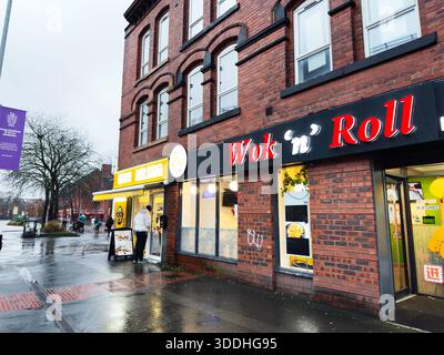 Manchester, Großbritannien - 06. Dezember 2025: Backsteinhaus in Manchester mit dem Wok and Roll Restaurant mit hellem Schild und Wet Street. Stockfoto