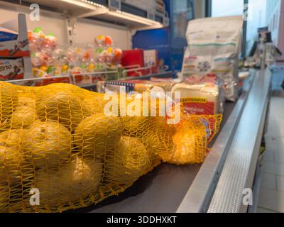 Deutschland Berlin 29. Dezember 2025. Beutel mit frischen Kartoffeln auf einem Supermarkt-Kassenförderband. Lebensmittel und verpackte Lebensmittel warten auf die Zahlung in einem Re Stockfoto