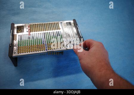 Hochwertige Nahaufnahme der Hand eines Chirurgen, die mit einer medizinischen Pinzette eine chirurgische Schraube aus einem orthopädischen Implantatträger auswählt. Die tr Stockfoto