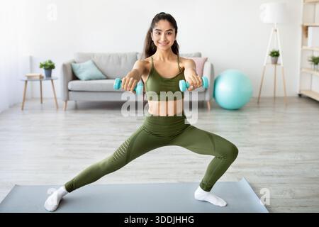 Krafttraining-Konzept. Athletische Indianerin, die in voller Länge Übungen mit Kurzhanteln macht Stockfoto