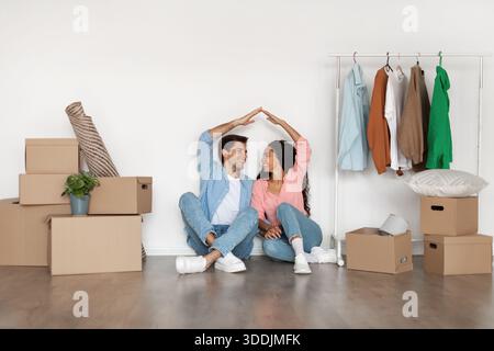 Happy Pärchen macht symbolisches Dach mit Händen in ihrem ersten neuen Zuhause Stockfoto