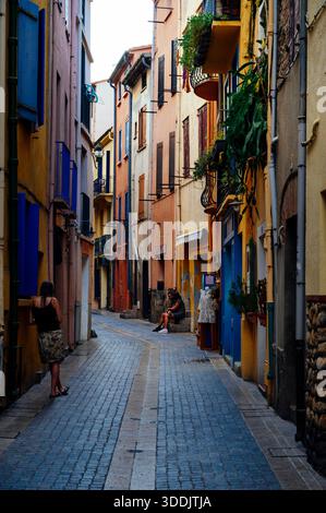 Frau sitzt auf einer Fensterbank in den Kopfsteinpflasterstraßen von Collioure, Cote Vermeille, Katalonien, Frankreich Stockfoto