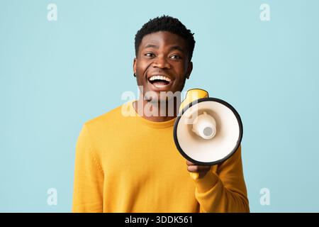 Fröhlicher schwarzer Kerl mit Megaphon, das Ankündigung macht Stockfoto