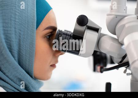 Seitenansicht Eines Islamischen Weiblichen Zahnarztes In Hijab Mit Einem Zahnmedizinischen Mikroskop Stockfoto