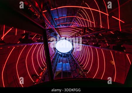 Das Innere des Schornsteinaufzugsschachts Battersea-Kraftwerk mit roten Neonlichtern und einer kreisförmigen Öffnung, von unten gesehen, mit Blick in einen hellen Himmel Stockfoto