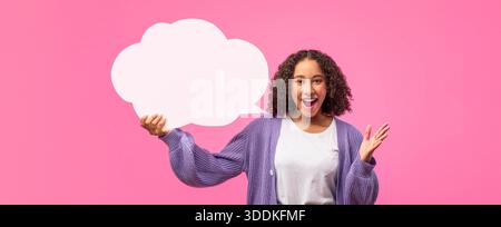 Frau, die Sprechblase mit rosa Hintergrund hält, während sie lächelt und ihre Hand winkt Stockfoto