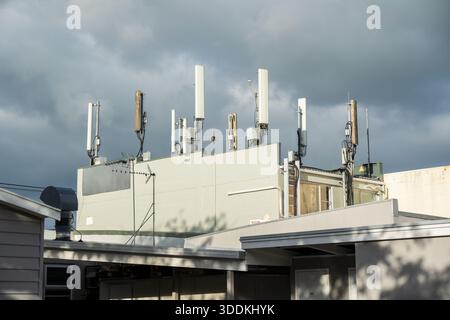 Mobiltelefontürme und Antennentafeln, die auf dem Dach eines Geschäftsgebäudes montiert sind, heben die städtische Telekommunikationsinfrastruktur hervor Stockfoto