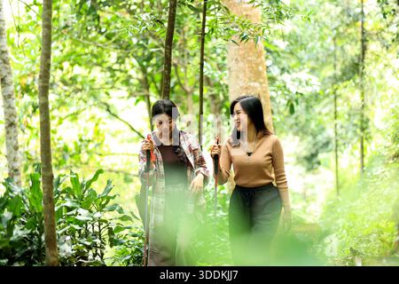 Zwei asiatische Freunde wandern in einem tropischen Wald im Freien und reden miteinander Stockfoto