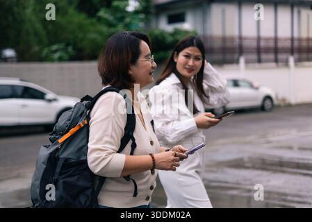 Asiatische Frauen gehen auf der Straße mit Smartphones mit Rucksacktechnologie Stockfoto