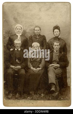 Original 1890er Jahre Schrank Karte Studio Porträt einer ernsthaft aussehenden Familie Gruppe von Erwachsenen, Männern und Frauen - eine Frau hat ein Schielen oder 'faul Auge', eine ältere Frau trägt Flämische Nationalkostüm, Männer tragen Uhrenketten 'Fobs'. Aus dem Studio von R. (Seraphinus Richardus) Heysse Walleghem in der Rue de la Station 18, Eecloo (Eeklo), Ostflandern, Belgien von 1885 bis 1908. Sleeves Fashion Datums Foto auf ca. 1890. Stockfoto