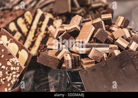 Auswahl an handwerklich hergestellten Pralinen, darunter Milch- und dunkle Schokoladentafeln mit Nüssen und einem Haufen von mehrschichtigen Fudge-Stücken, die eine Vielzahl von Konfekt bieten Stockfoto
