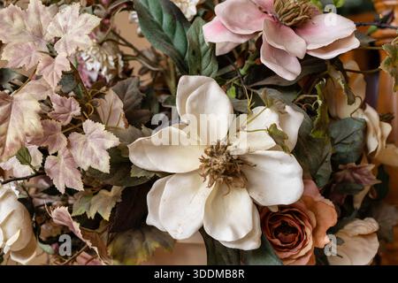 Weiches, Vintage-inspiriertes Bouquet aus Seiden-Magnolien, hellen Rosen und gemischten grünen Blättern in gedämpftem Rosa und weiß, romantische dekorative Einrichtung für zu Hause Stockfoto