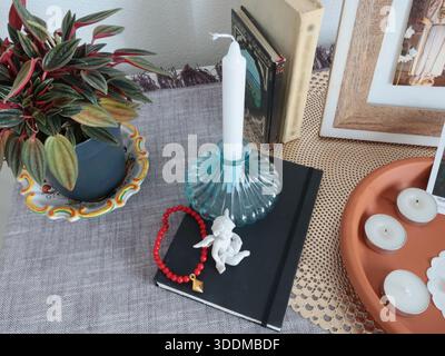 Katholische Gläubige Ecke zu Hause. Symbole und Kerzen. Engel Figur und Armband. Glaube, Symbole und Traditionen. Stockfoto