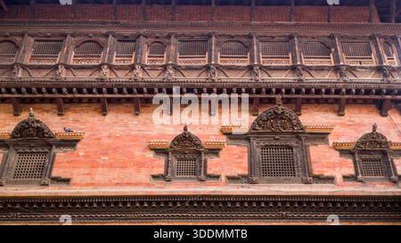 Aufwändige Holzschnitzereien und dekorative Fensterrahmen zieren eine Ziegelfassade im traditionellen architektonischen Stil. Stockfoto