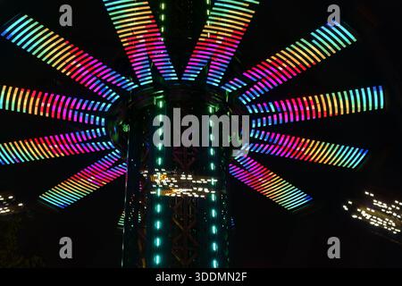 Drehende Lichter eines Vergnügungsparks Karussells bei Nacht, aufgenommen mit langer Belichtung. Stockfoto