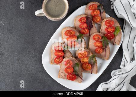 Hausgemachte Sandwiches mit putenpastete und Kirschtomaten, auch eine Tasse Kaffee auf grauem Hintergrund, Blick von oben Stockfoto