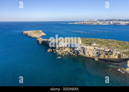 Die raue, sonnendurchflutete Landschaft von St. Paul's Island, Mistra Bay, St. Paul's Bay, Mal steht von der Luft aus im Kontrast zu dem schroffen weißen Leuchtturm Stockfoto