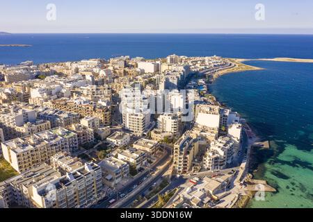 Aus der Vogelperspektive auf das türkisfarbene Meer, Gebäude entlang der Küste, Bugibba, St. Paul's Bay, Malta. Stockfoto