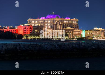 Abu Dhabi, VAE - 24. November 2025: Das majestätische Emirates Palace Mandarin Oriental leuchtet mit warmen goldenen und roten Lichtern vor einem dunkelblauen Himmel Stockfoto