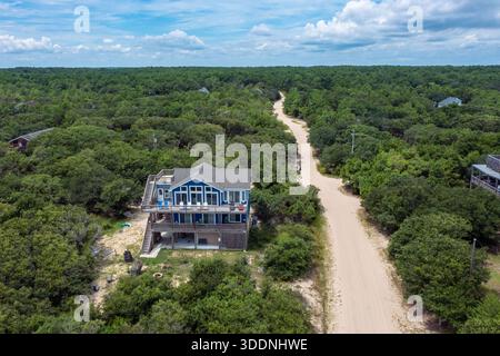 Luftaufnahme eines Strandurlaubswohnheims neben einer unbefestigten Straße in einem Wald in Carova Beach North Carolina Stockfoto