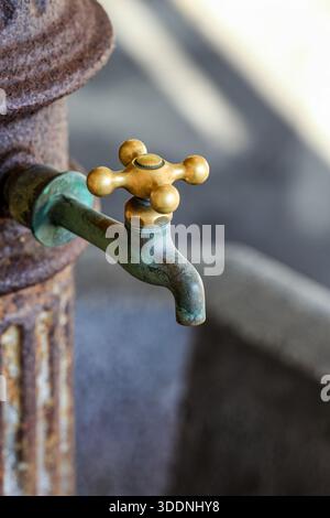 Nahaufnahme eines alten Messingwasserhahns, der in der öffentlichen Toilette installiert wurde. Stockfoto